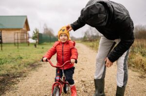 Parent helping a child learn to ride a bike