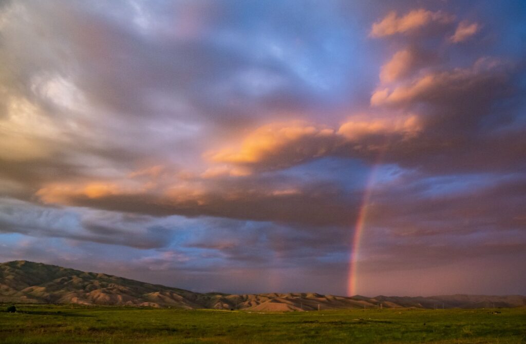 Rainbow breaking through storm clouds over the countryside